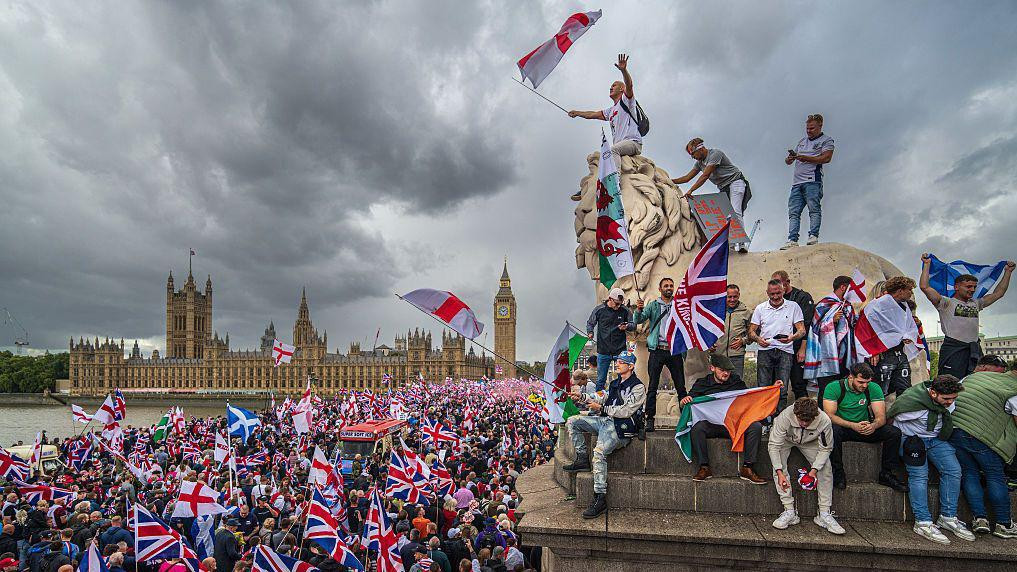 Okupljeni mašu zastavama tokom skupa Ujedinite Kraljevstvo u blizini parlamenta 13. septembra 2025. u Londonu