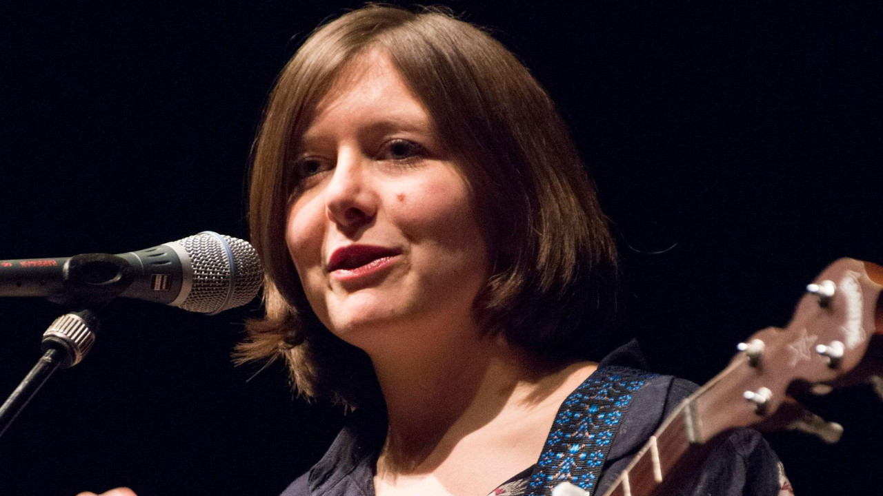 Emili Portman sa gitarom i mikrofonom na bini