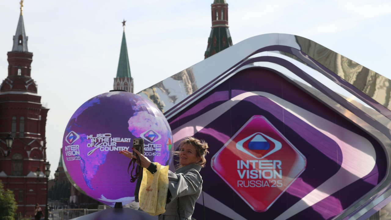 Devojka na Crvenom trgu u Moskvi pred kojom je globus ukrašen rečima „INTERVIZIJA RUSIJA'25“ i sloganom „Muzika u srcu naše zemlje“