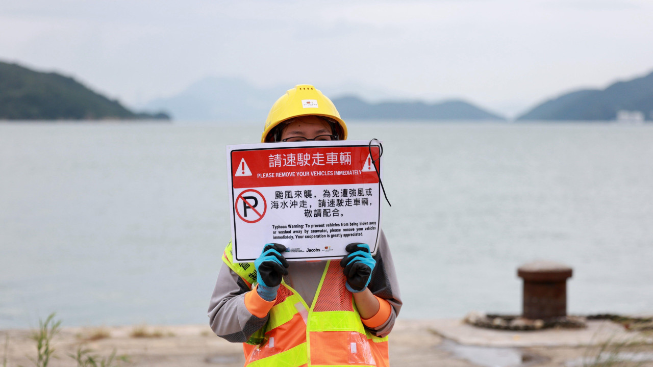 žena drži tablu sa upozorenjem na tajfun, žena drži tablu sa upozorenjem na nevreme 