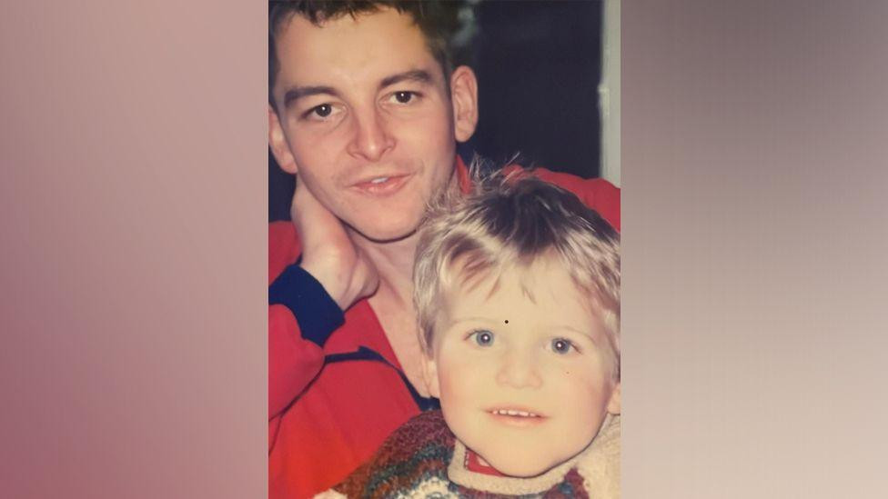 Stara porodična fotografija na kojoj Fred prislanja glavu na ruku, dok mu je u krilima Džek kao dečak