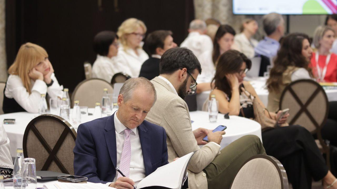 Vilijam Midlton u teget odelu sa roze kravatom sedi za stolom i čita