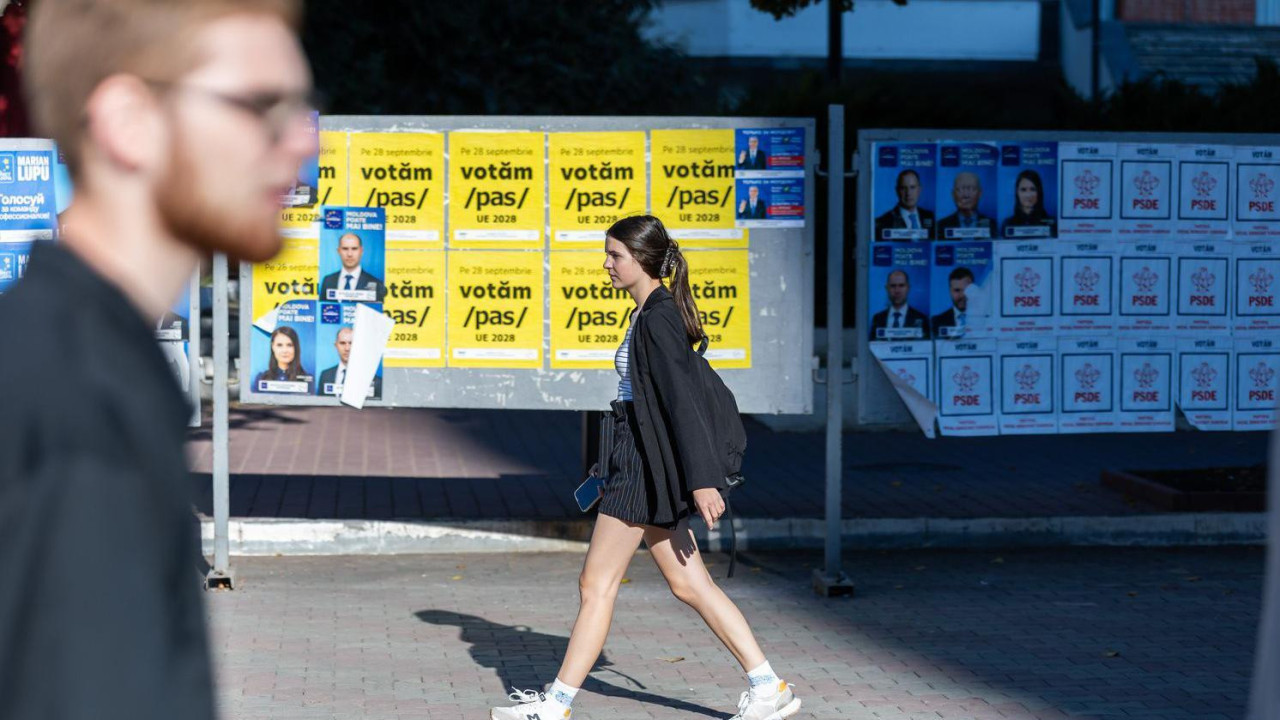 Devojka hoda ulicom pored bilborda na kojima su politički plakata koji pozivaju na predstojeće izbore