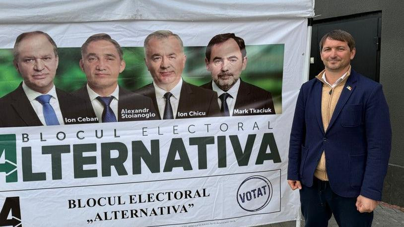 Učesnik kampanje Alternativa pored plakata sa fotografijama i imenima kandidata