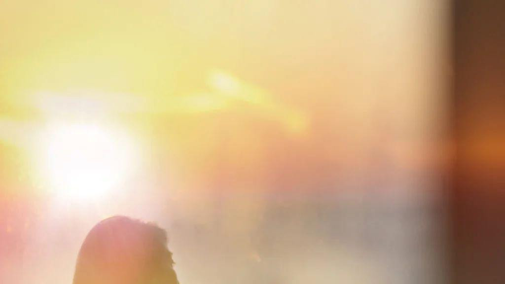 žena drži šoljicu kafe sa obe ruke i gleda levo od sebe