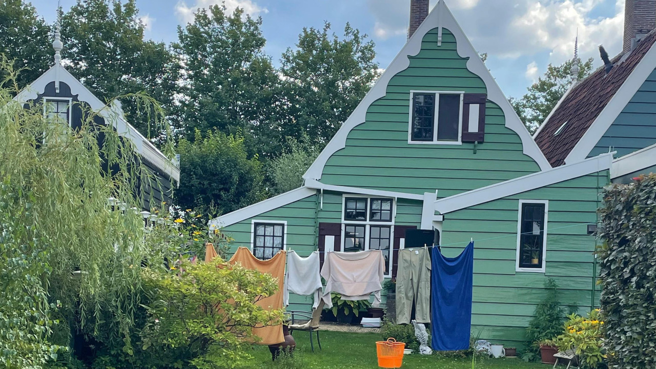 kuće ofarbane u zeleno. Ispred je žica za veš na kojoj je zakačena odeća 