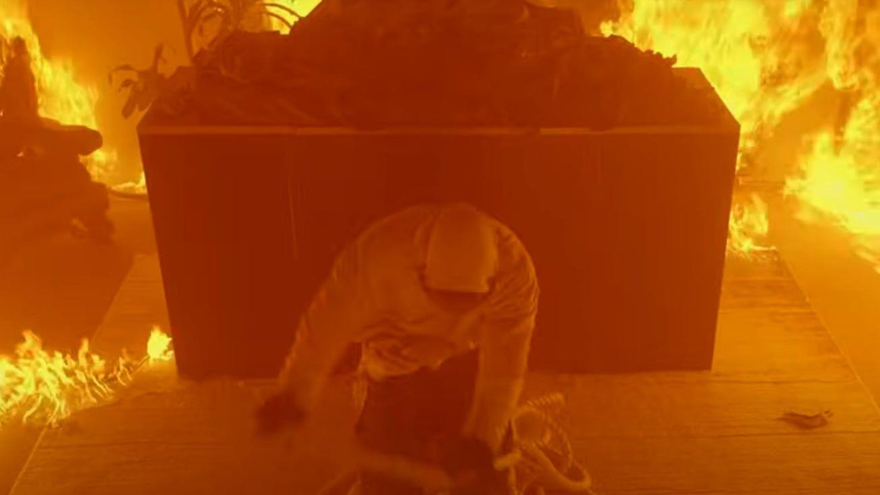 muškarac skida konopce sa sebe dok oko njega gori vatra 