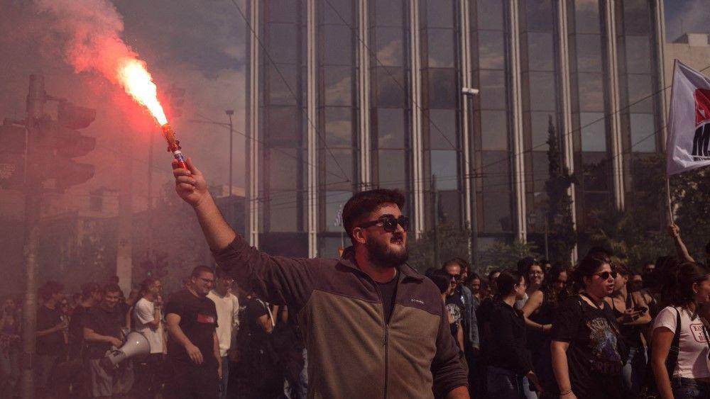 muškarac drži baklju tokom štrajka radnika u Atini