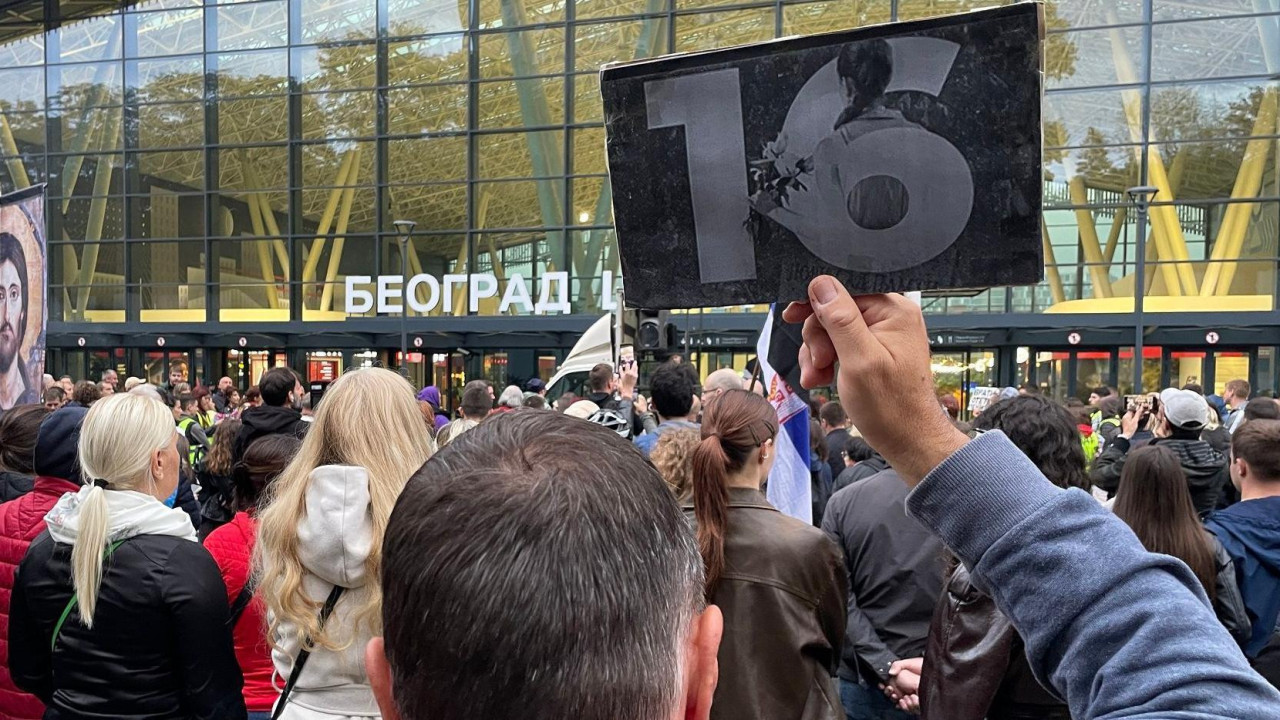 Muškarac okrenut leđima drži podignut papir sa brojem 16 tokom protesta