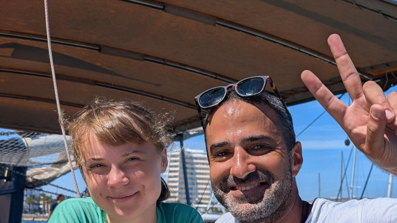 Jusef Samour na brodu Julara sa klimatskom aktivistkinjom Gretom Tunberg - on podiže znak „v kao pobeda“ rukom i oboje se smeju. 