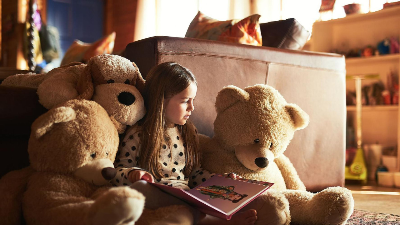 Devojčica čita knjigu plišanim medvedima