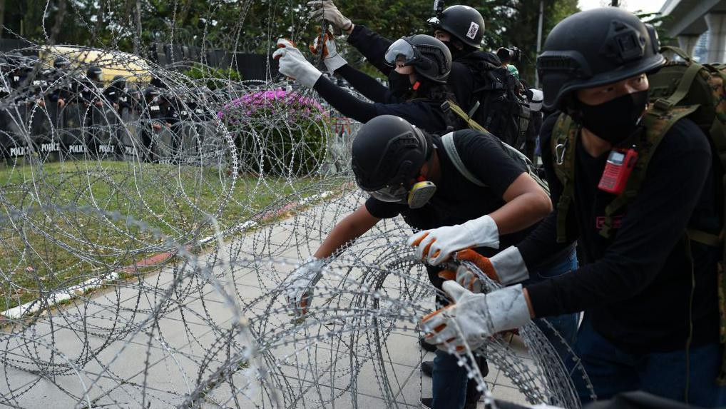 Tajlandski antivladini demonstranti, u punoj zaštitnoj opremi, uklanjaju bodljikavu žicu tokom demonstracija ispred sedišta Kraljevske garde u Bangkoku, 29. novembra 2020. godine