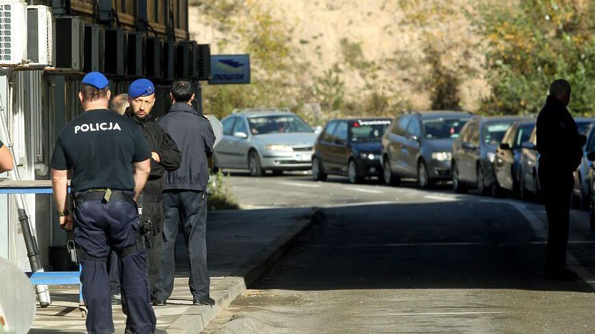 Nekoliko muškaraca u uniformama policije Kosova na prelazu Jarinje, u daljini se vidi kolona automobila