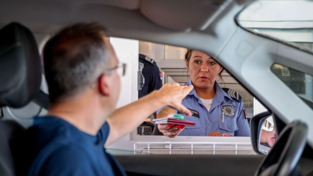 Granična službenica u uniformi policije Srbije pruža dva srpska pasoša čoveku koji je pružio ruku krou prozor automobila
