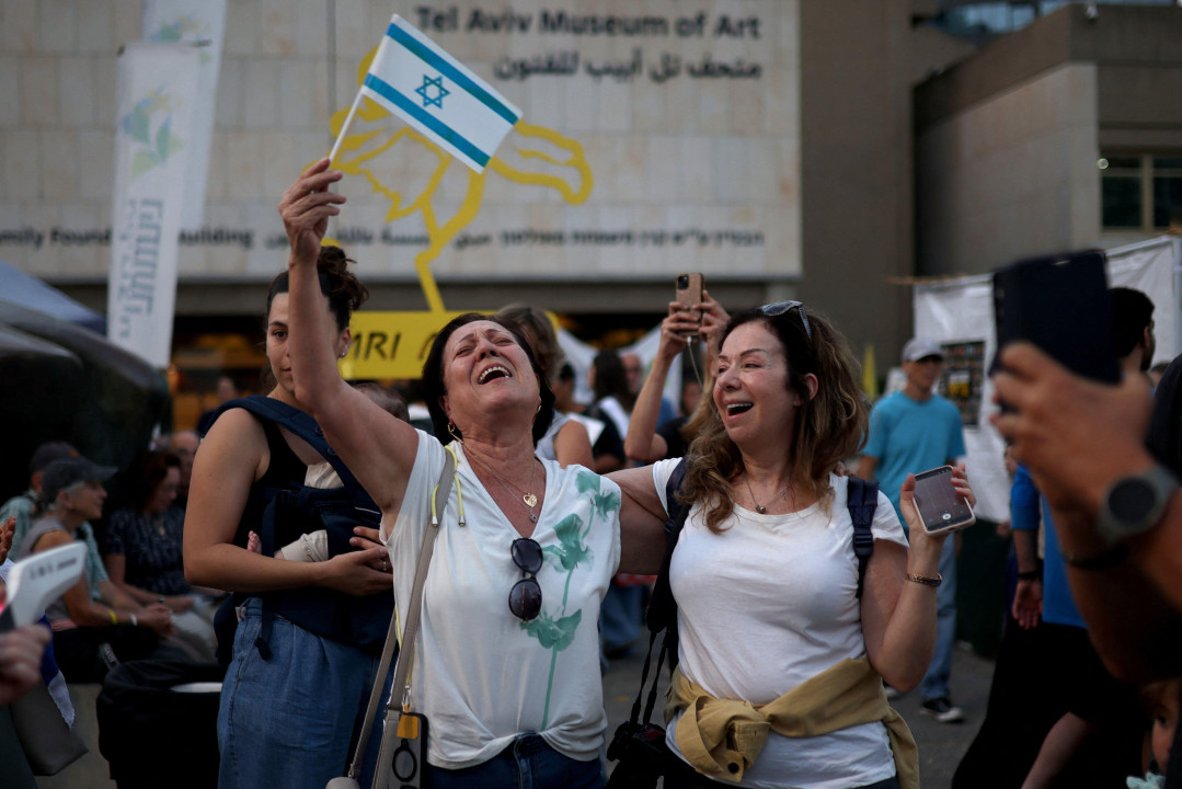 Dve žene slave u belim majicama, jedna maše izraelskom zastavom