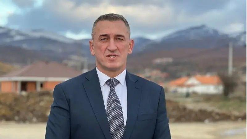 Nenad Rašić u teget odelu s kravatom, uz kosovski krajolik u pozadini