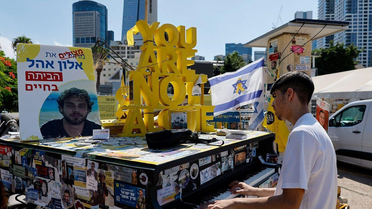 A boy plays the piano at "Hostages Square", after a ceasefire between Israel and Hamas in Gaza went into effect, in Tel Aviv, Israel