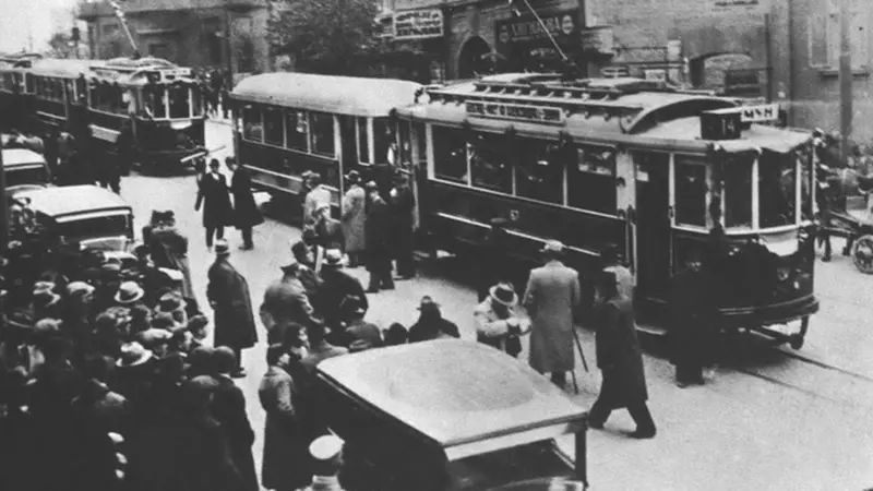 Tramvaj na ulicama Beograda dok ljudi šetaju pored njega, crno-bela fotografija