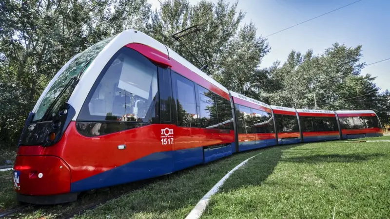 Savremeni tramvaj u bojama državne zastave Srbije okružen zelenilom