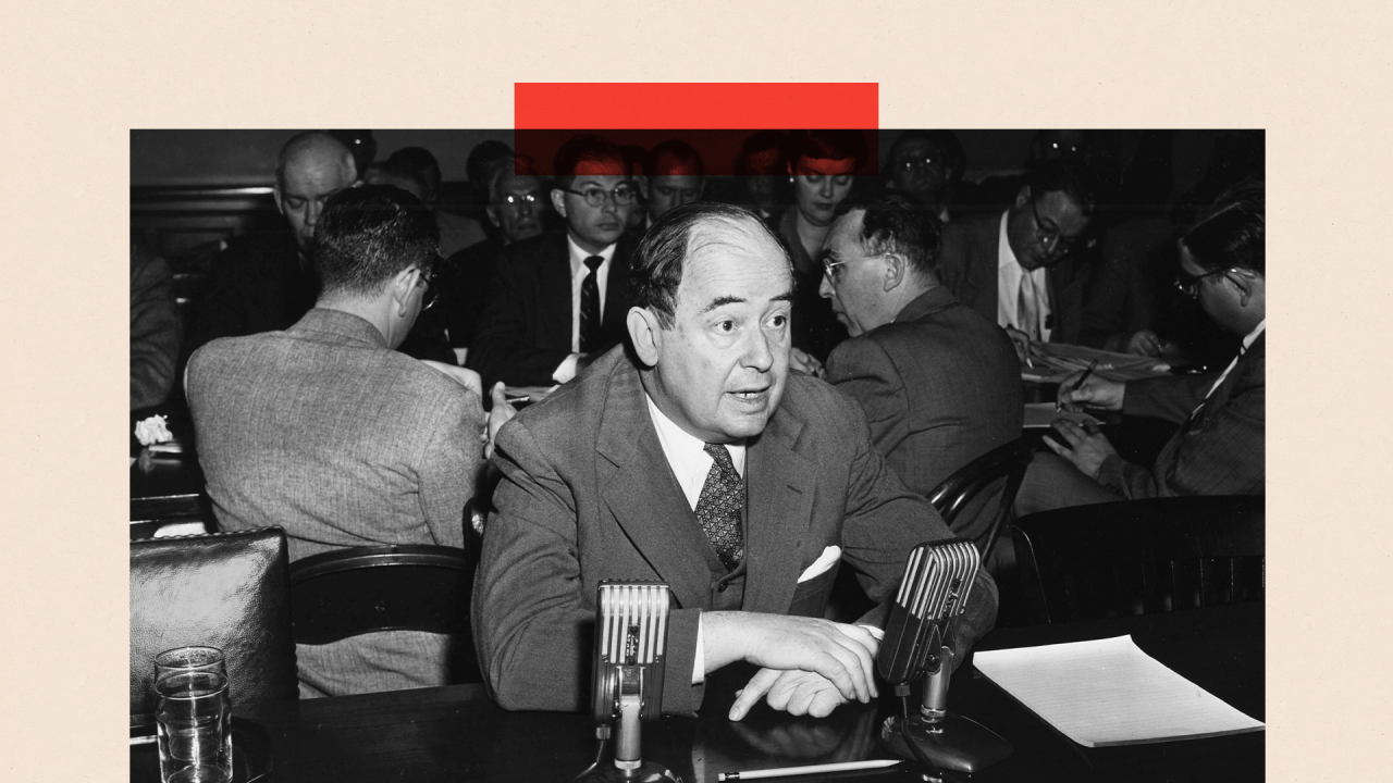 Crno-bela slika Džona fon Nojmana u odelu kako sedi za stolom