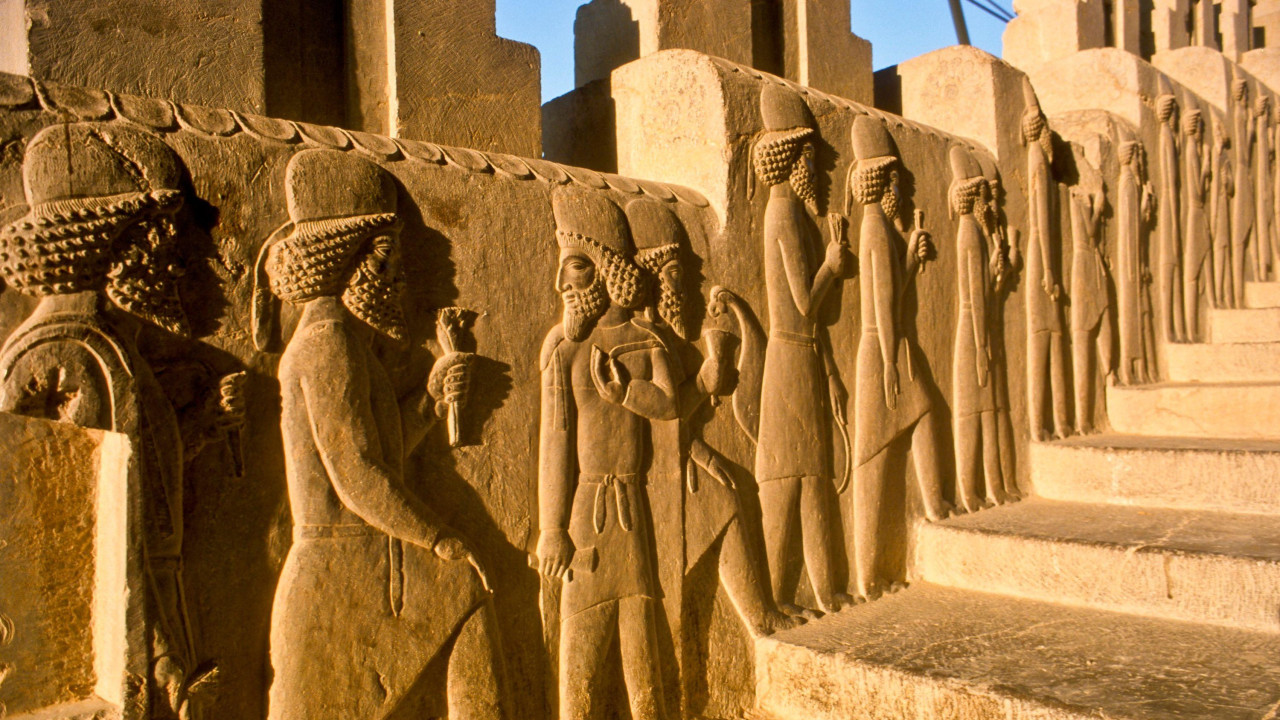 Figure krase stepenište u palati u Persepolju. Jarka sunčeva svetlost obasjava red ljudi koji izgledaju kao da se penju uz stepenice