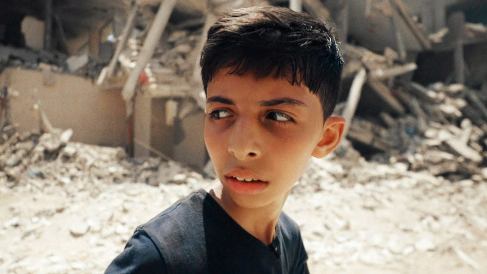 Abdullah Al-Yazouri walking in front of a demolished building in the BBC documentary Gaza: How To Survive A Warzone