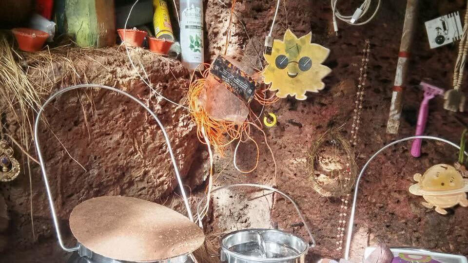 Unutar pećine u kojoj je Nina Kutina živela sa svojom decom: u malom udubljenju između korenja drveta nalazi se nekoliko metalnih posuda, dečji ranac i razni predmeti, uključujući i ukrasne