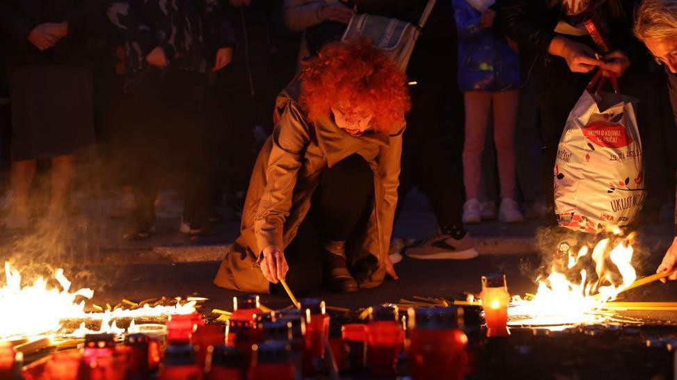 žena pali sveću ispred Železničke stanice za stradale u padu nadstrešnice