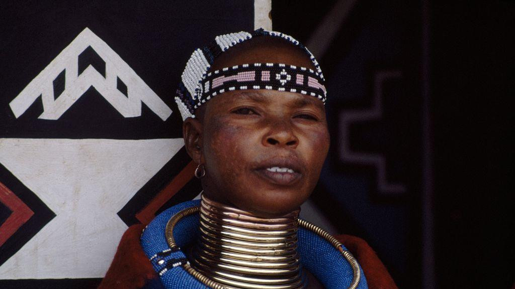 Slika žene sa zlatnim prstenjem nanizanim oko vrata