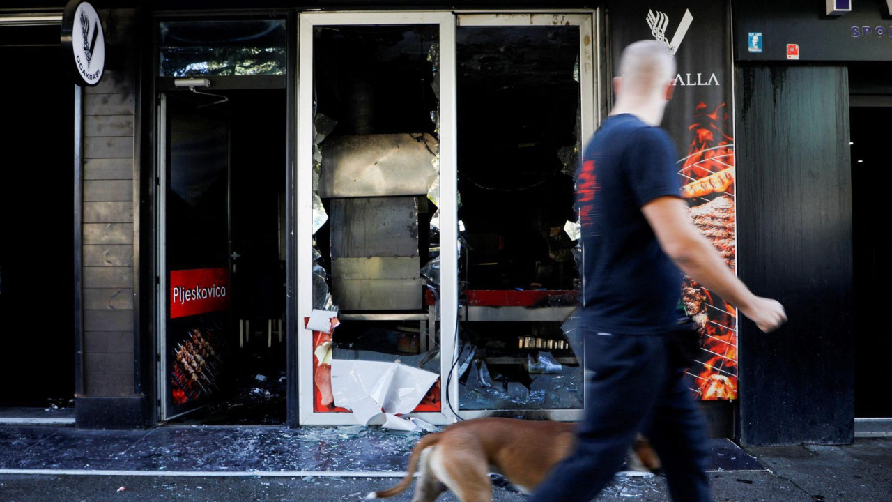 Muškarac i pas prolaze pored zapaljenog kafića