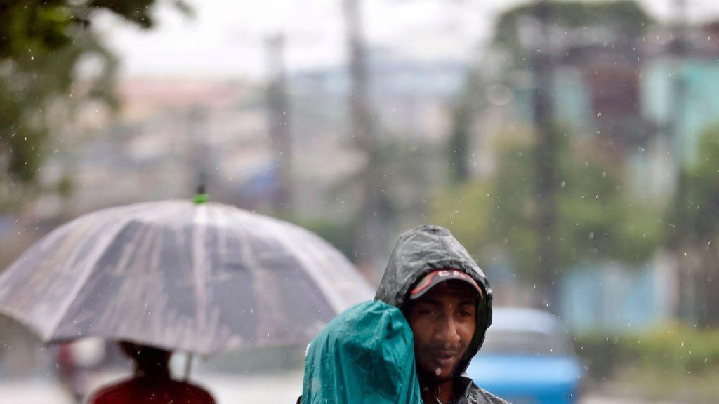 muškarac nosi dete dok pada kiše, oboje su u kabanicama, uragan, uragan melisa