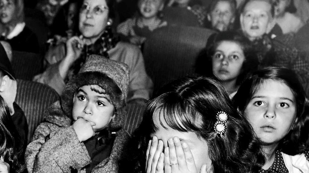 devojčica drži ruke preko očiju, oko nje su druge uplašene devojčice