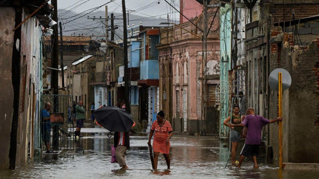 Četvoro ljudi na poplavljenim ulicama posle uragana Melisa na Kubi