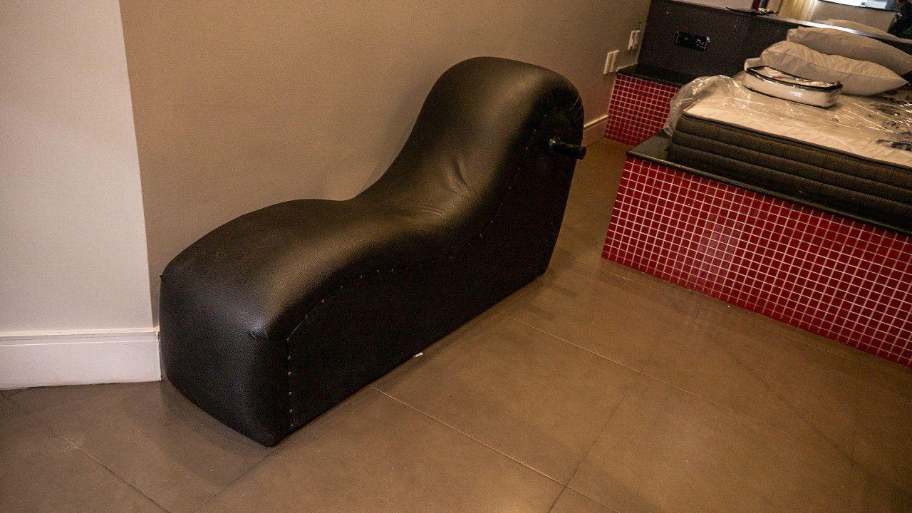 Zakrivljeni, crni kauč pored dušeka i beli dušek