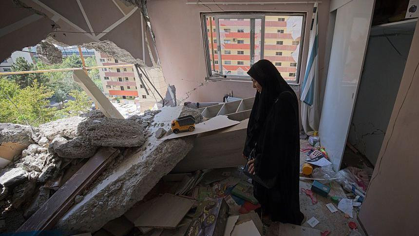 Žena stoji u razrušenom stanu 