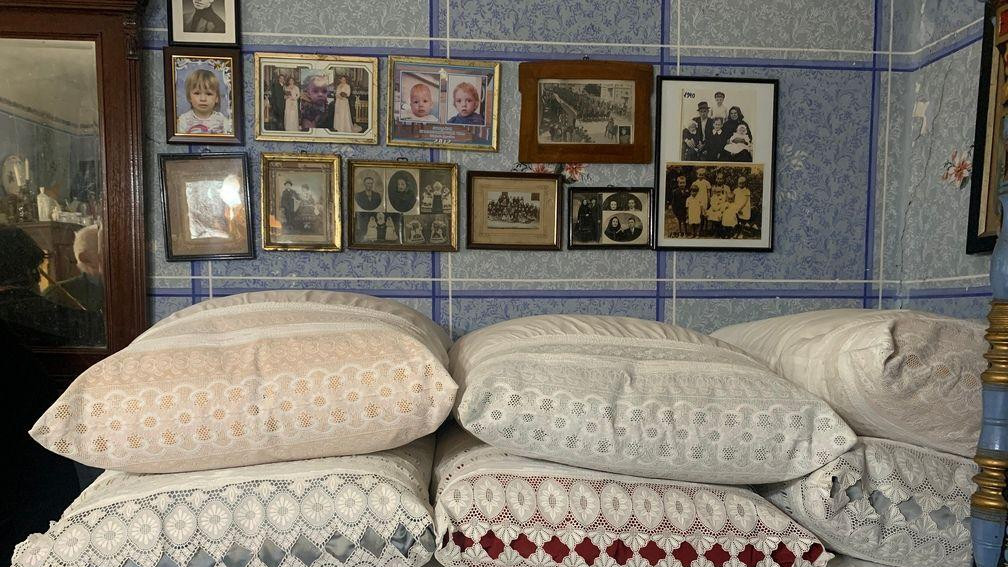 Šareni jastuci naređani na krevetu u sobi koja je okrečena u plavo