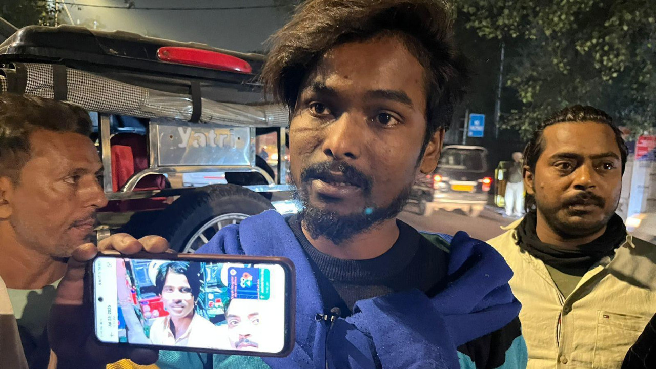 Muškarac drži telefon na kome je fotografija nestalog muškarca posle eksplozije automobila u Delhiju 