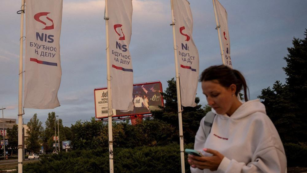 A woman holding a phone walks past white flags
