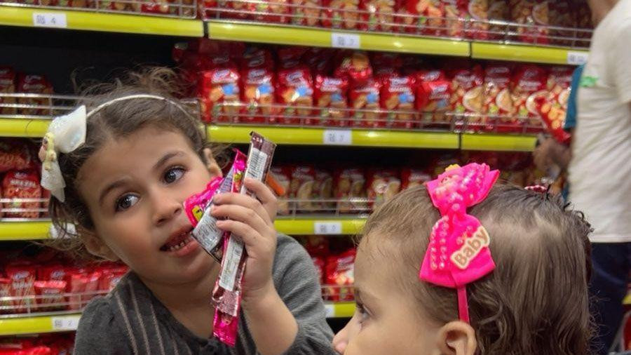 devojčice u prodavnici, jedna drži slatkiš  