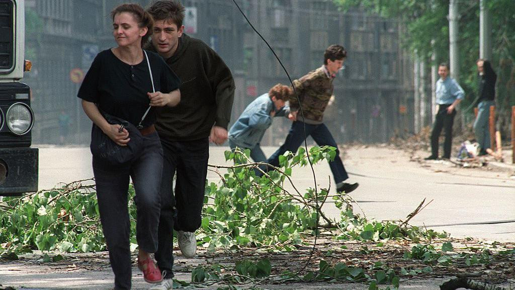 Stanovnici Sarajeva trče kroz raskrsnicu poznatu po snajperskoj aktivnosti nakon što je granata pala u centru grada 20. juna 1992. godine