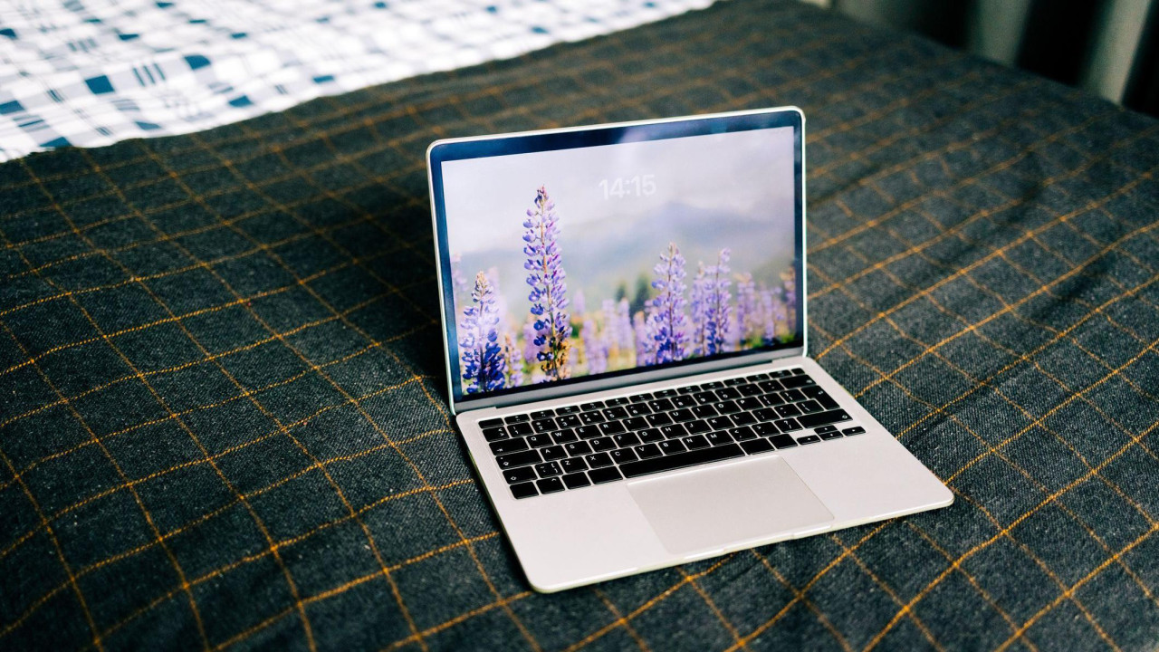 Laptop na krevetu na čijem dekstopu su ljubičasti cvetovi lavande