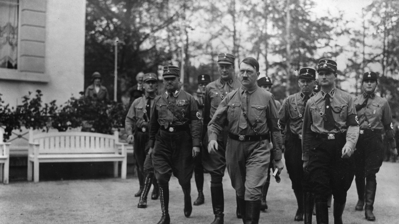 Crno-bela slika Hitlera kako hoda sa uniformisanim ljudima iza sebe