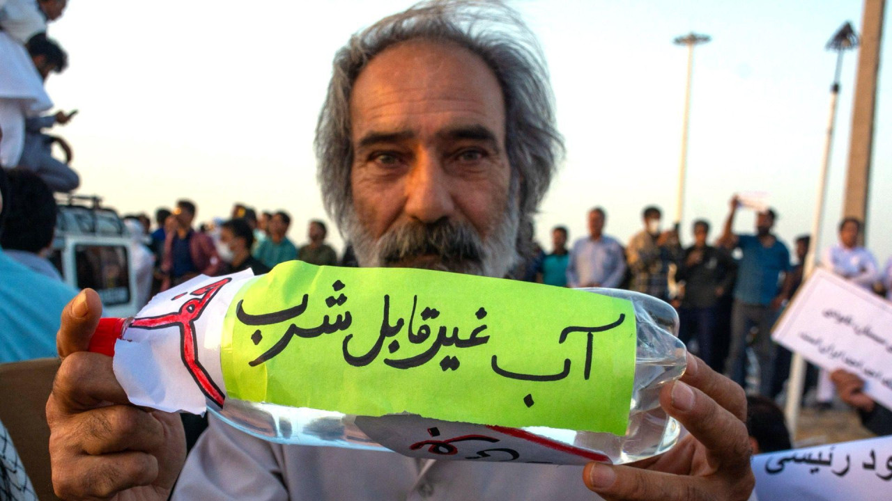 Upozorenje: Voda nije za piće natpis je na flaši koju drži čovek koji protestuje u Iranu, suša u iranu, iran ostaje bez pijaće vode