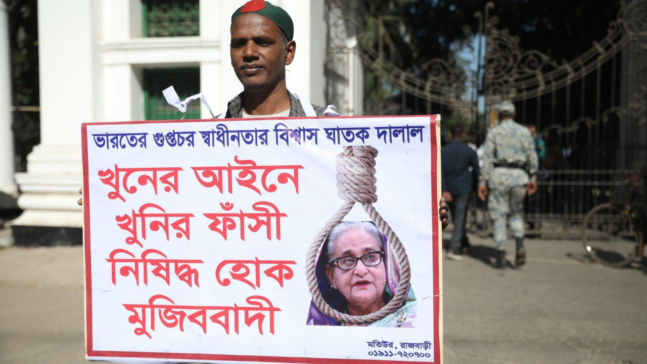 Muškarac drži u ruci transparent na kojem je slika bivše premijerke Šeike Hasani