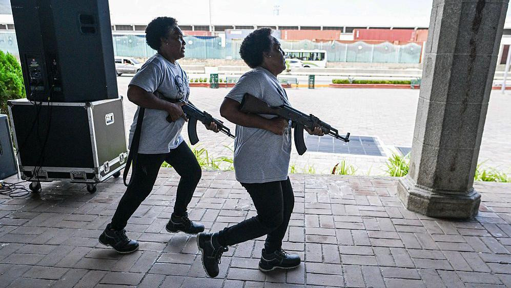 Sestre bliznakinje Karmen i Marija Santana, pripadnice Bolivarske nacionalne milicije, trče sa puškama u rukama tokom vojne vežbe u La Gvairi, Venecuela, 8. oktobra 2025. godine