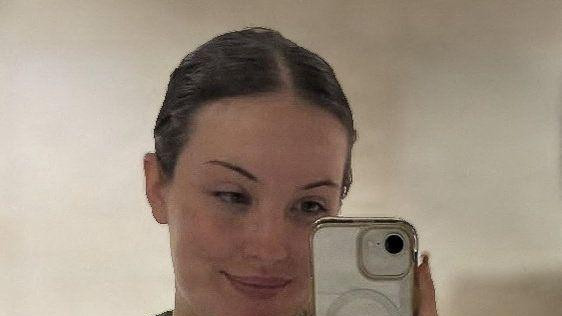 Devojka u vojničkoj uniformi gleda u ogledalo i slika se