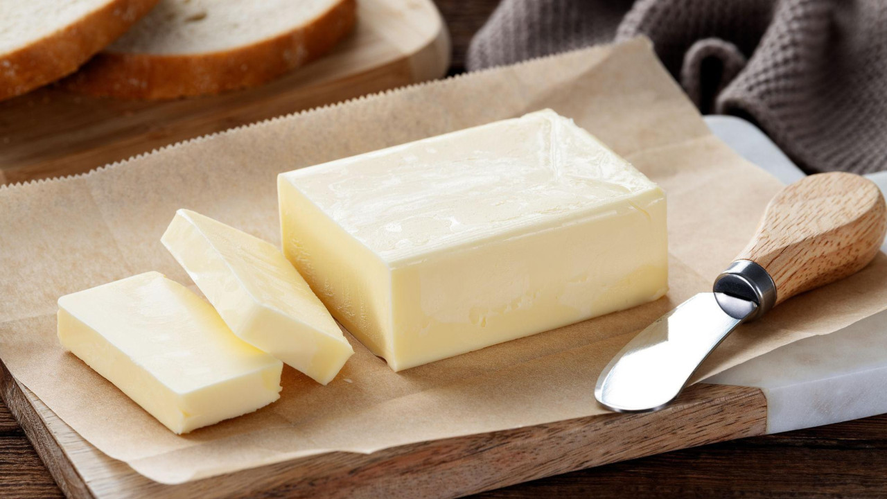 Isečeni komadići putera na drvenoj dasci 