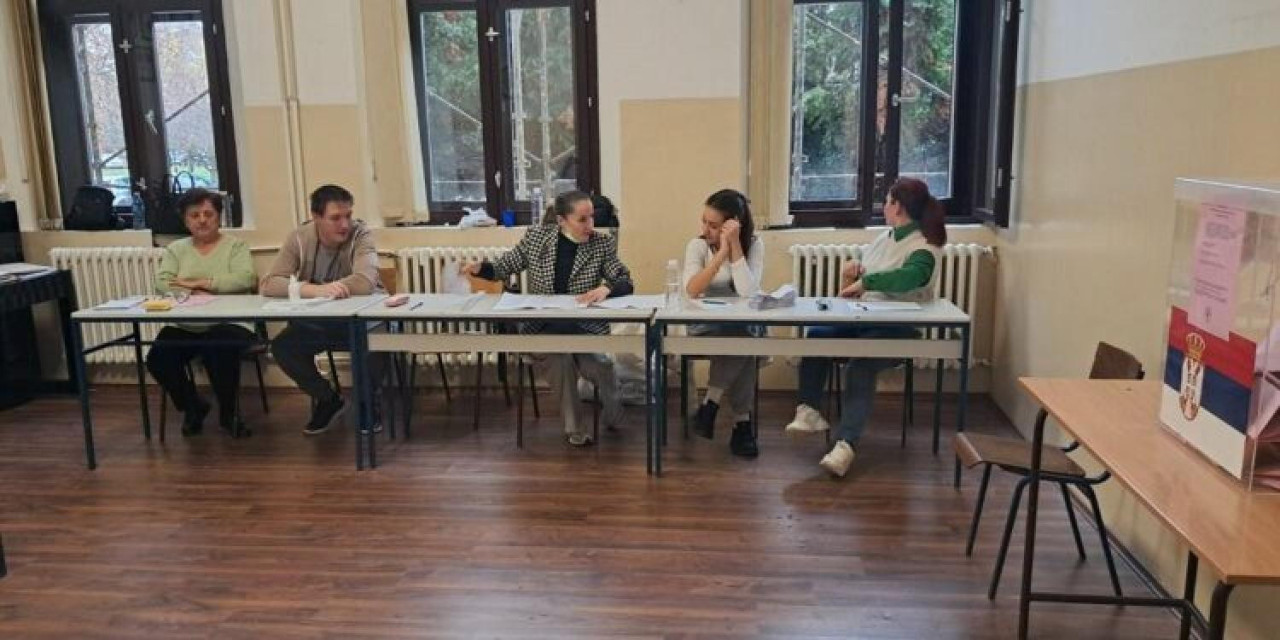 Nekoliko ljudi sedi za drvenim klupama