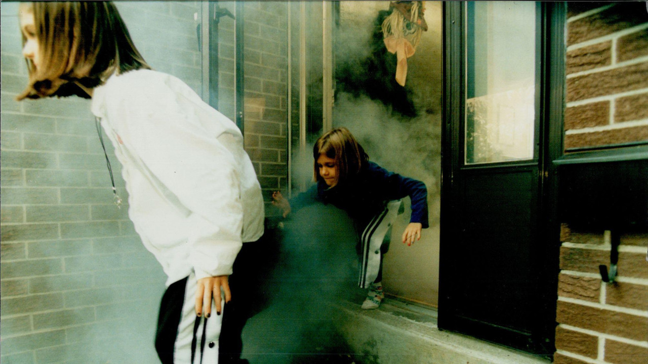 Dve devojčice iskaču iz zadimljene zgrade tokom vežbe evakuacije