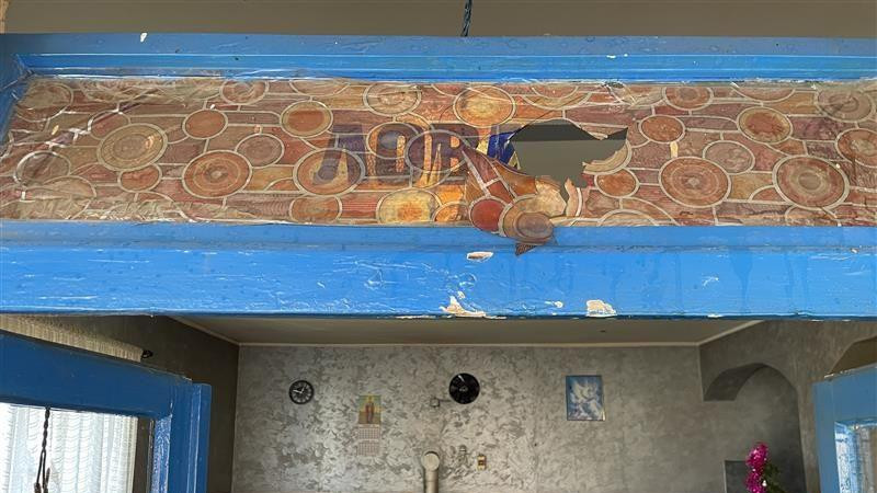 Unutrašnjost kafane: nekoliko drvenih stolova, šporet na drva, plava vrata iznad kojih je ćirilično napisano Lovac